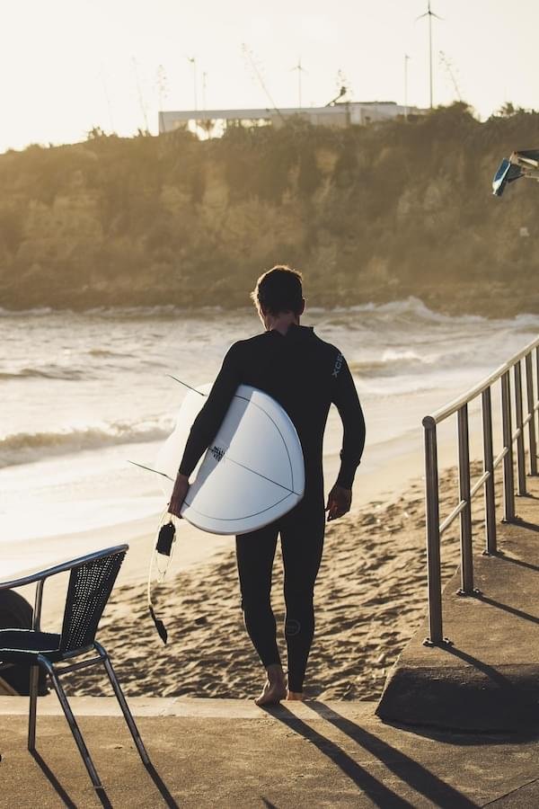 A surfer with is board riding on the Sand on this way to the Sea, sepia color